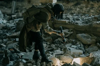 Silhouette en tenue de survie fouillant des décombres, dans une ambiance sombre