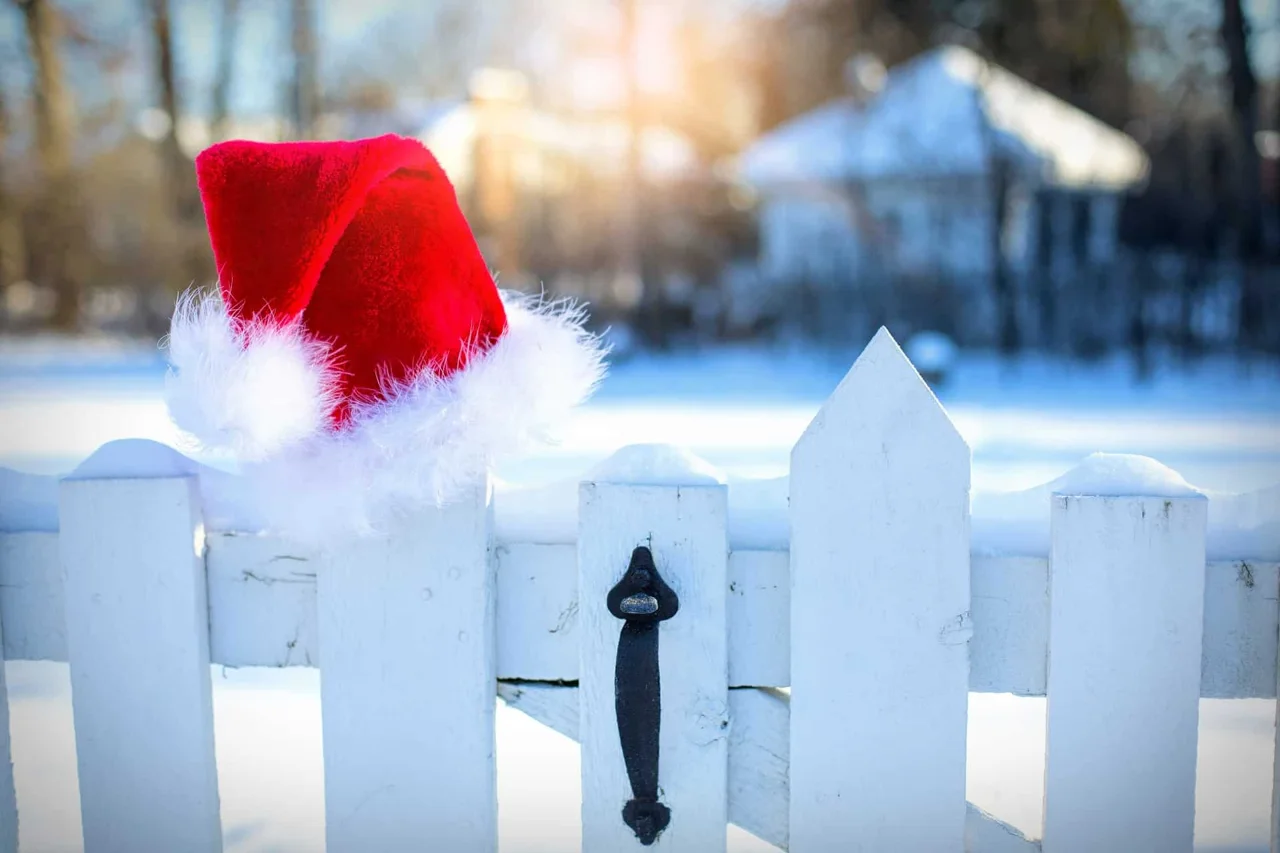 Bonnet de père Noël posé sur une barrière blanche enneigée