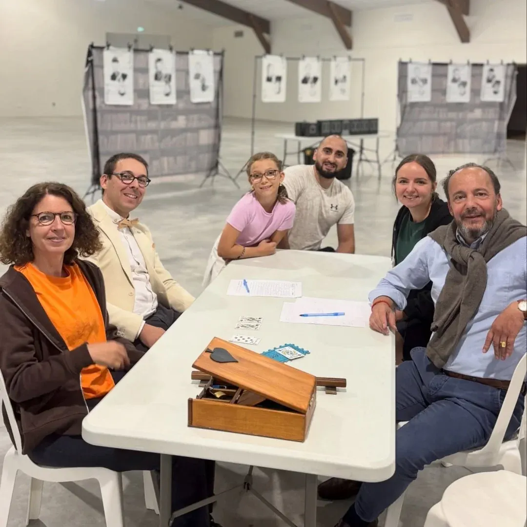 Équipe souriante autour d'une table avec un coffret en bois, portraits suspendus en arrière-plan