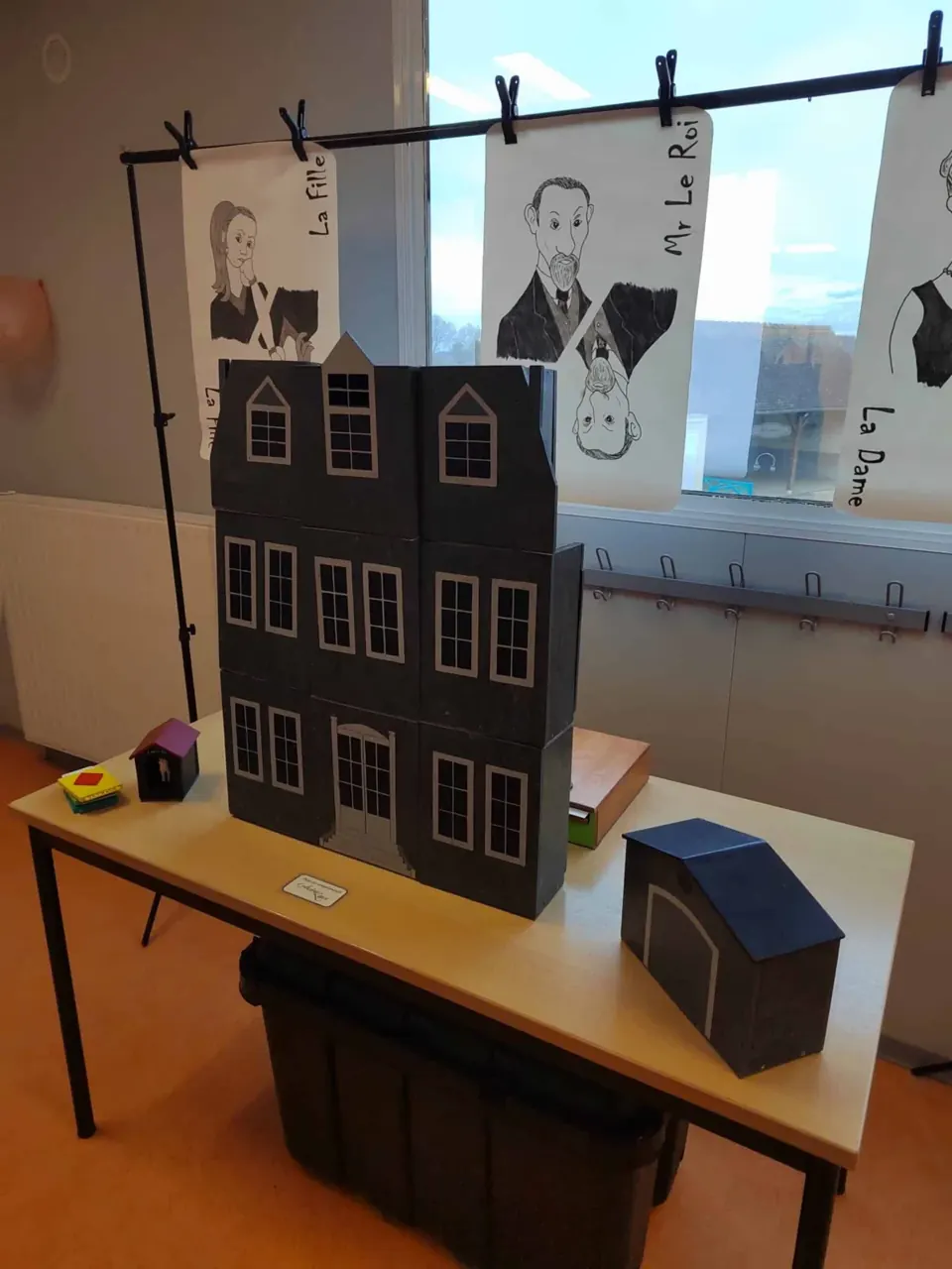 Maquette de maison noire et portraits suspendus sur une table de jeu