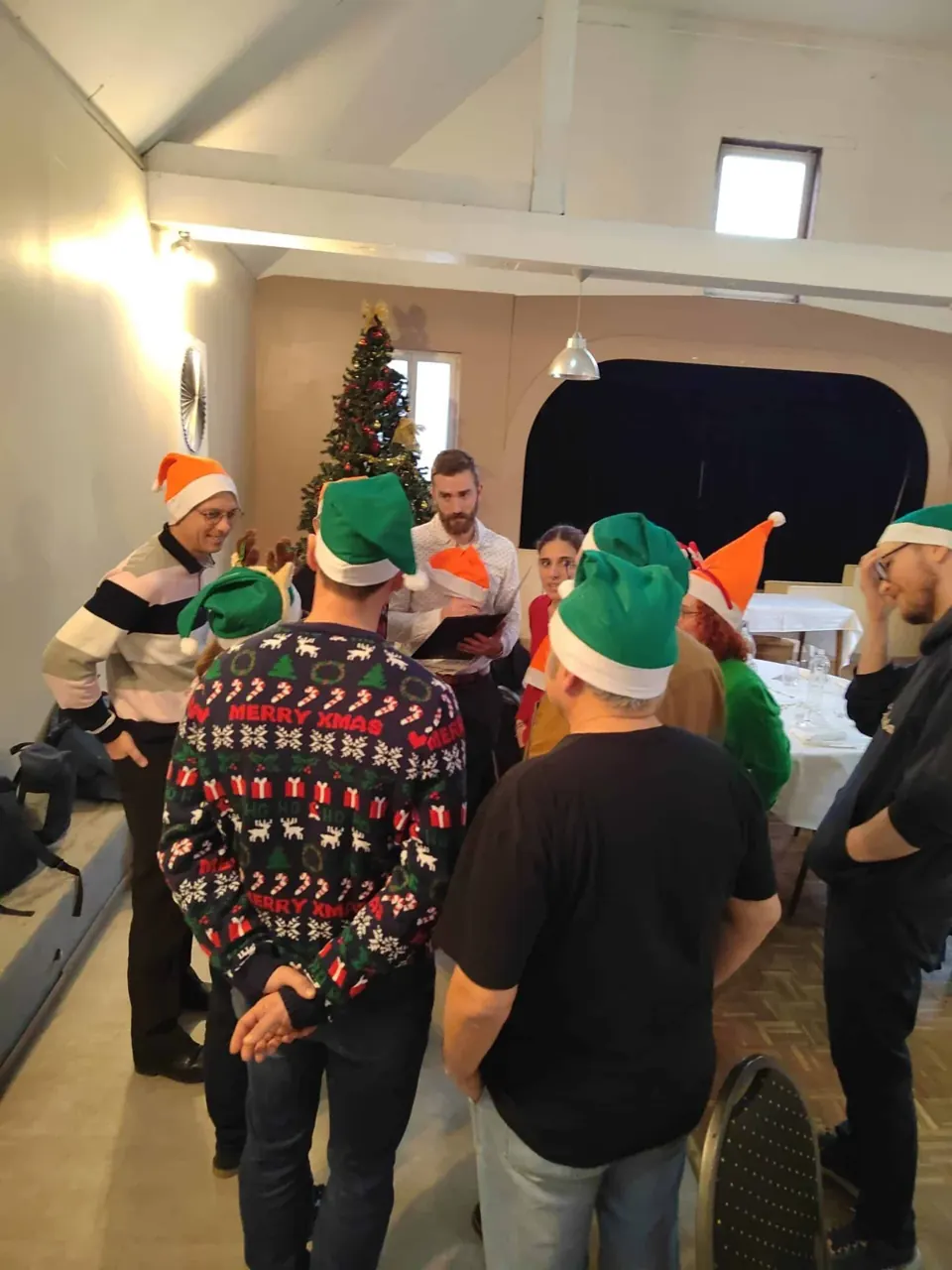 Groupe de joueurs en bonnets de lutin verts et pulls de Noël dans une salle de réception