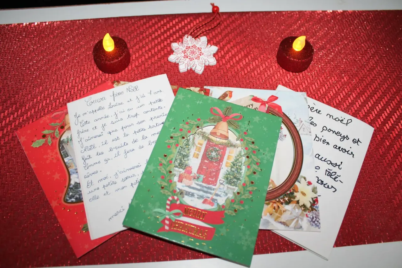 Carte de vœux, lettres manuscrites et bougies sur une nappe rouge