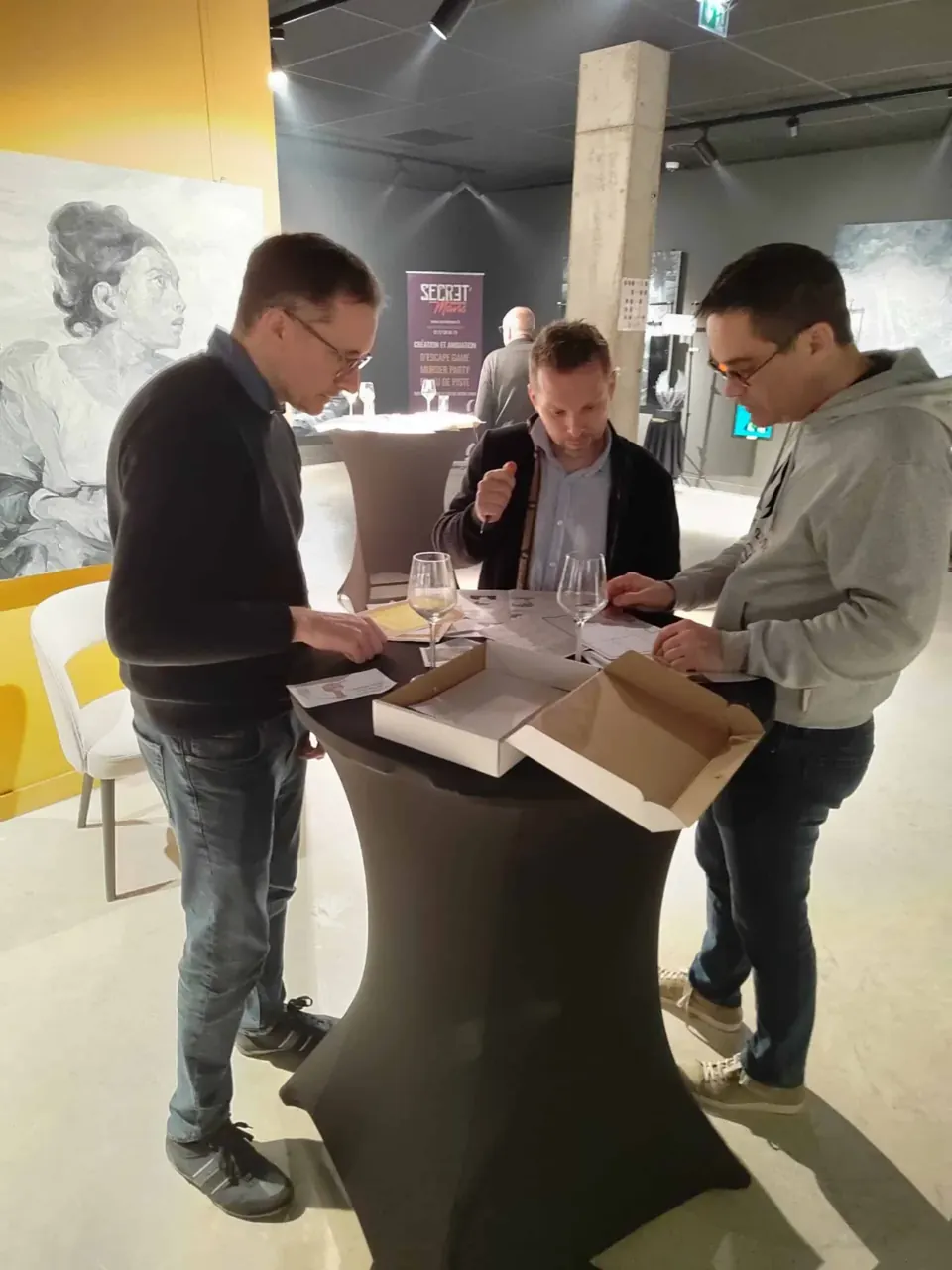 Trois joueurs examinent un dossier d'enquête sur une table haute