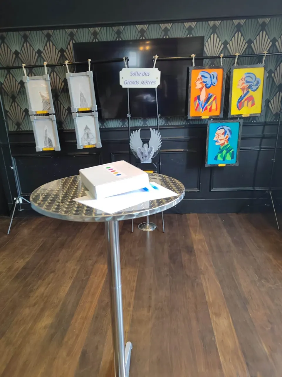 Table ronde avec un coffret blanc devant des tableaux colorés suspendus