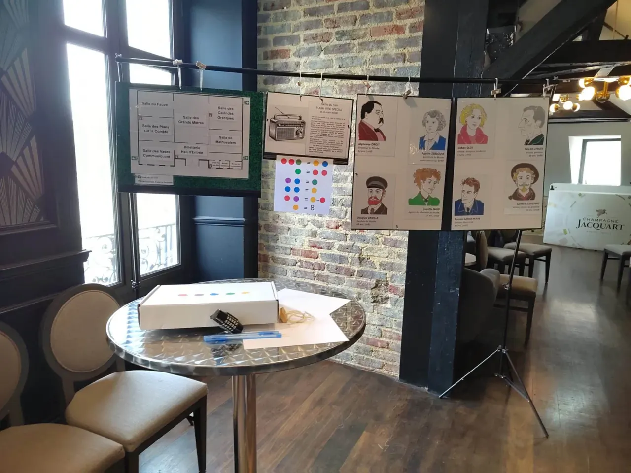 Portraits suspendus et table ronde avec un coffret, devant un mur de briques